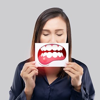 A woman holding an illustration of diseased gums in front of her mouth