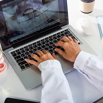 a dentist looking at an X-ray of a mouth on a laptop