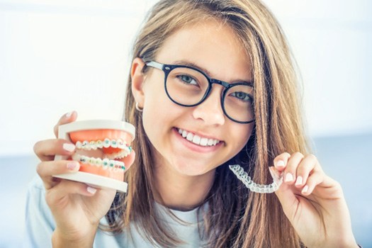 Girl holding braces in one hand and clear aligner in the other