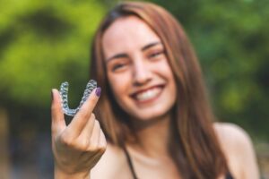 Woman holding Invisalign in foreground.